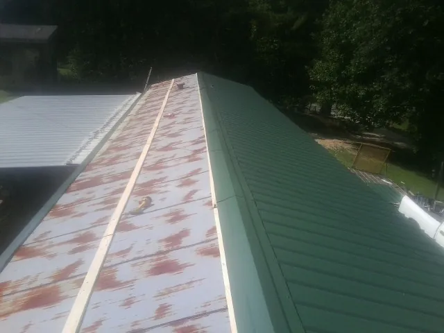 Old rusted panels beside newly installed green metal roofing — Wind Damage Roof Repair by Roofing Brothers in Pittstown