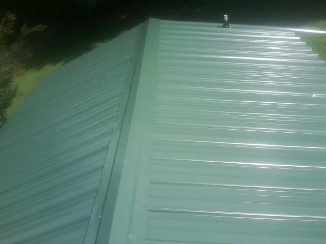 New green metal panels meeting at the ridge of a roof — Flat Roof Repair work by our crew in Pittstown