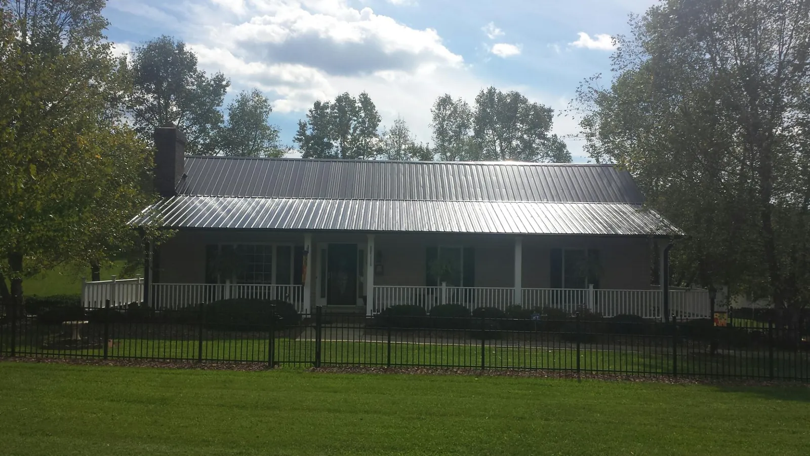 Gray metal roof on a brick ranch with a full width front porch — Gutter Guard Installation work by our crew in Pittstown