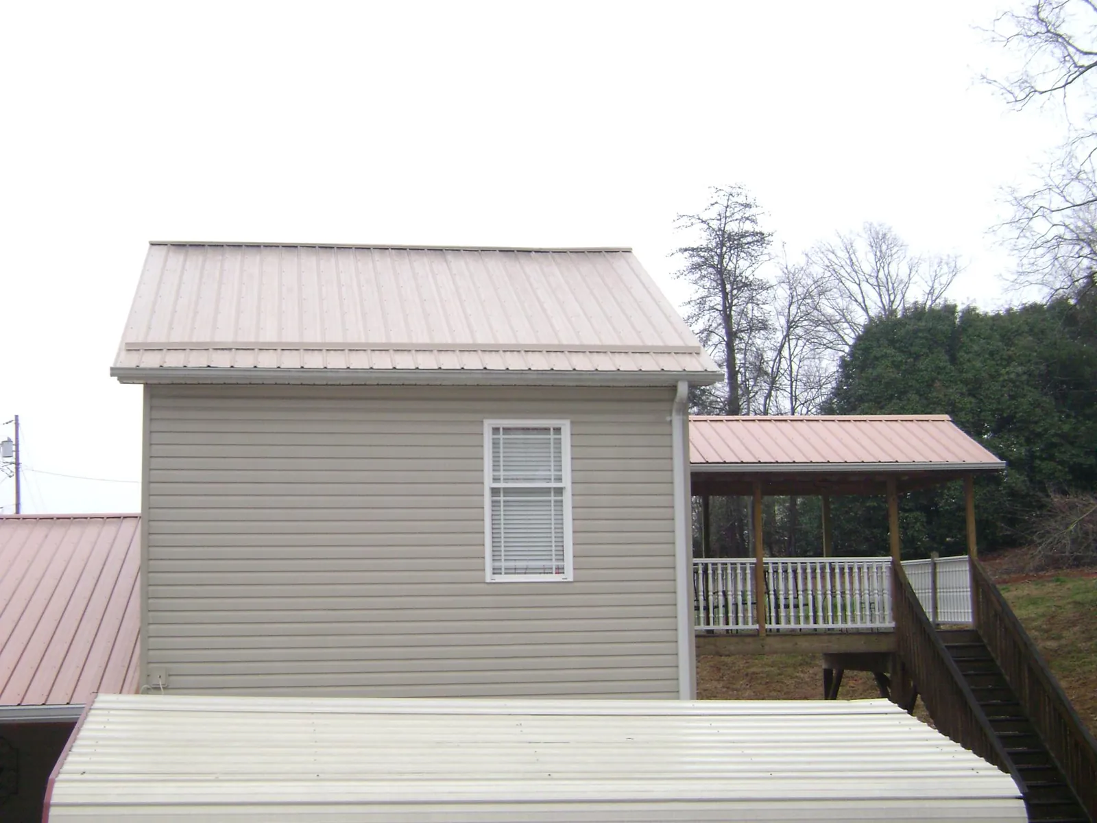 Tan metal roofs on a two story addition and attached porch, from a Roof Replacement job in Pittstown